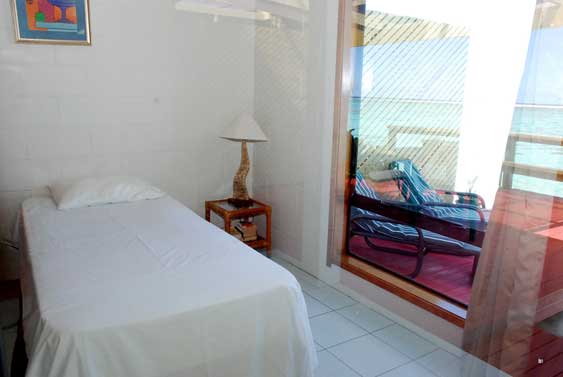 second bedroom with a single bed and a large floor to ceiling window giving more views of the loving ocean