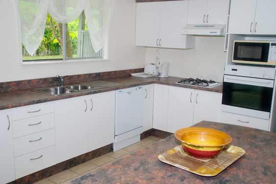 open plan kitchen with breakfast bar, microwave full fridge/freezer, oven, 4-burner stove top, double sink and dishwasher